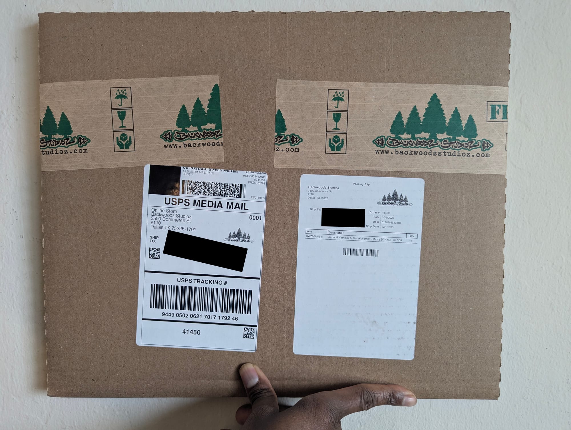 A packaged vinyl record with Backwoodz Studioz packing tape. The 'Ship To' address has been redacted with black bars.