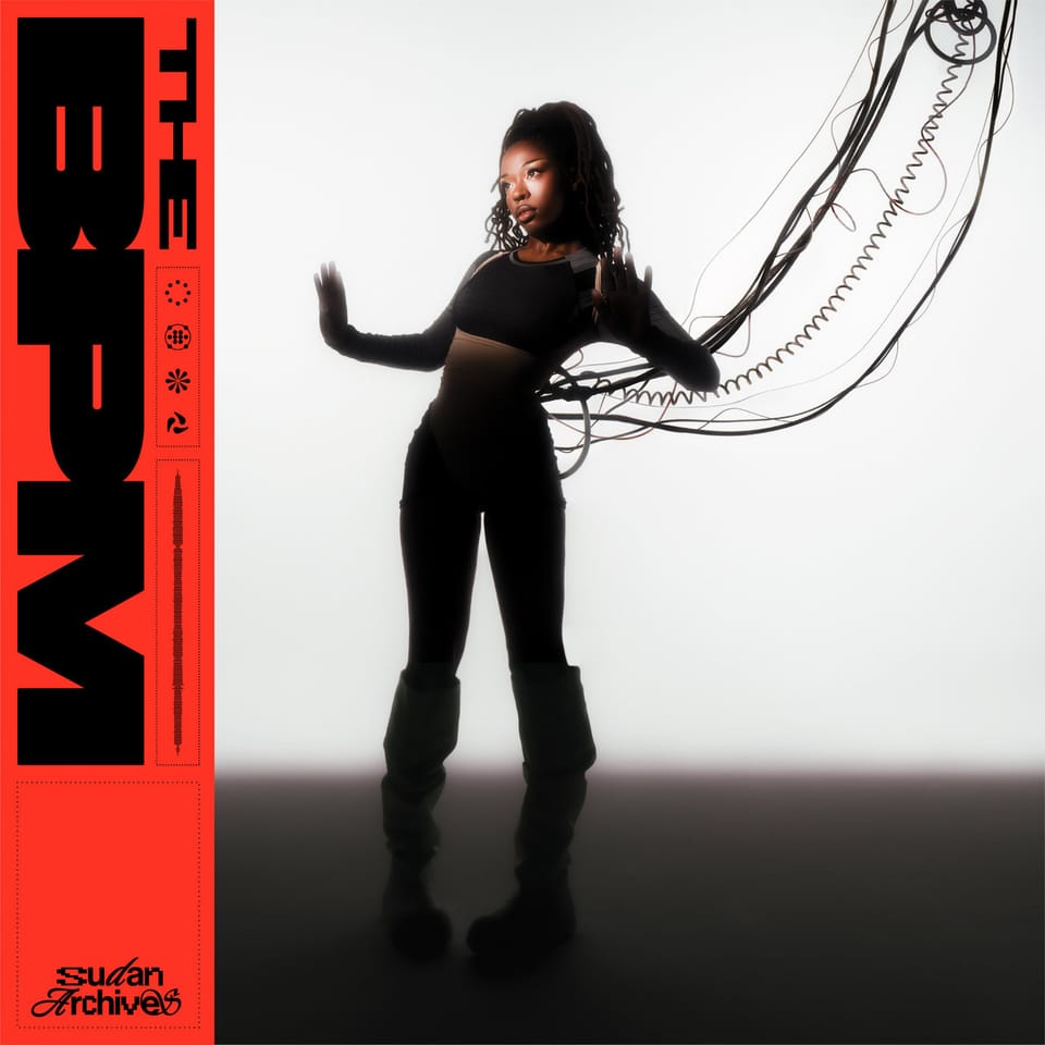 The cover for Sudan Archives' 'THE BPM'. Sudan is posed with her arms up at her sides with cables and wires connected to her back as she looks at a light to her right.
